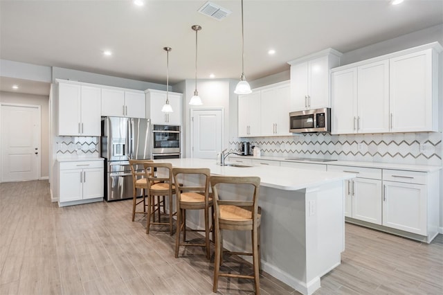 kitchen featuring decorative light fixtures, white cabinets, and appliances with stainless steel finishes