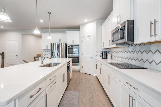 kitchen with white cabinets, appliances with stainless steel finishes, hanging light fixtures, and backsplash