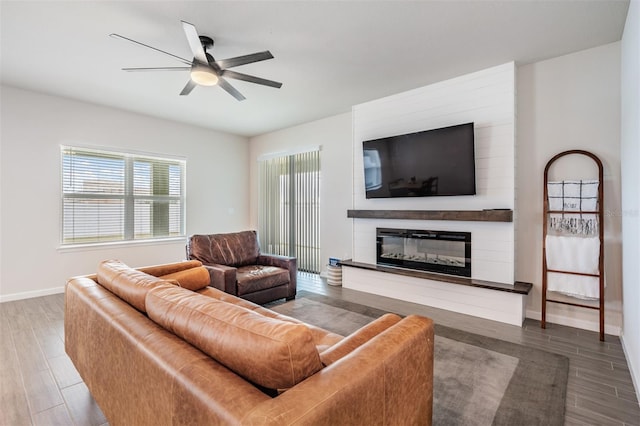 living room with wood-type flooring, ceiling fan, and a fireplace