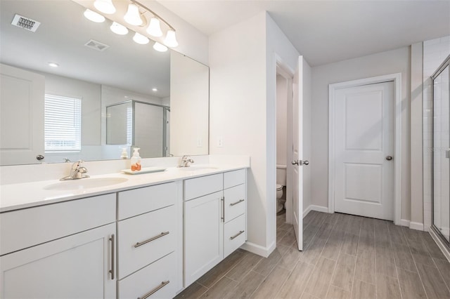 bathroom with walk in shower, vanity, and toilet