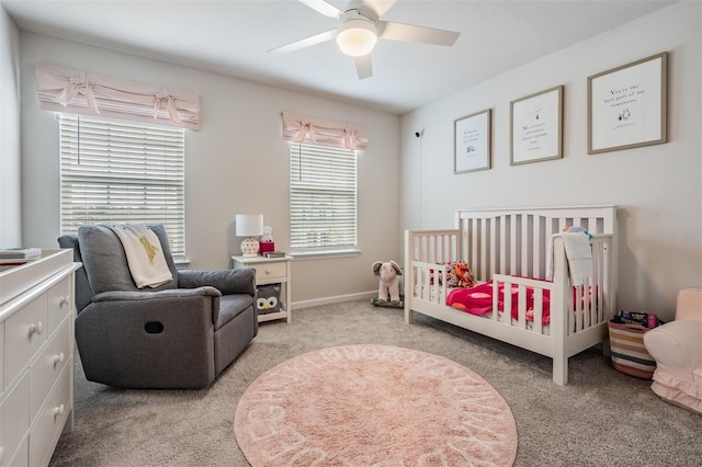 bedroom featuring a crib, light colored carpet, and ceiling fan