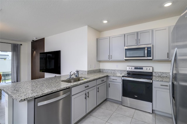 kitchen with kitchen peninsula, appliances with stainless steel finishes, sink, light tile patterned floors, and light stone countertops