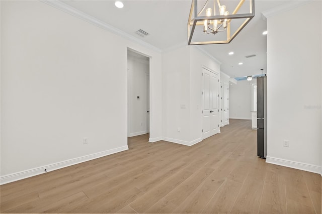 unfurnished room with light hardwood / wood-style flooring, ornamental molding, and a notable chandelier