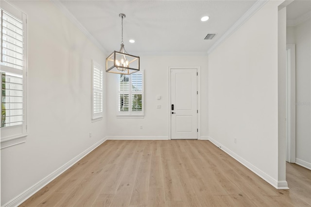 foyer entrance with crown molding, light hardwood / wood-style flooring, and a notable chandelier