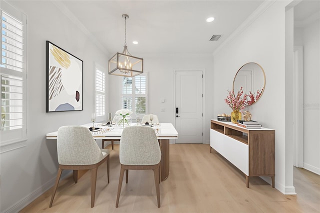 dining room with a chandelier, crown molding, and light hardwood / wood-style flooring