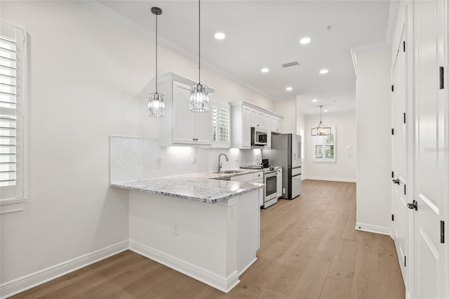 kitchen with hanging light fixtures, white cabinets, kitchen peninsula, and appliances with stainless steel finishes