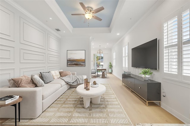 living room with ceiling fan, ornamental molding, plenty of natural light, and a tray ceiling