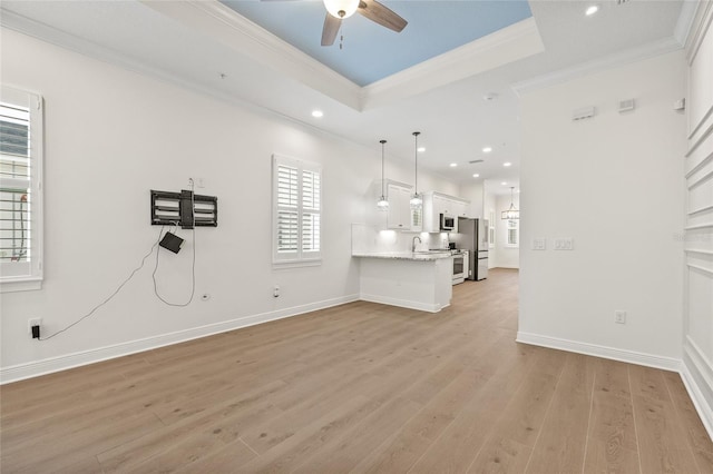 unfurnished living room featuring ornamental molding, a raised ceiling, and light wood-type flooring