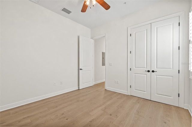 unfurnished bedroom with light wood-type flooring, ceiling fan, electric panel, and a closet