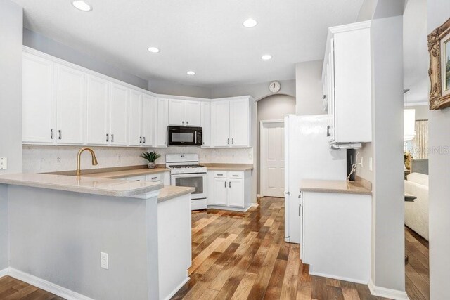 kitchen featuring tasteful backsplash, light hardwood / wood-style flooring, kitchen peninsula, white appliances, and white cabinets