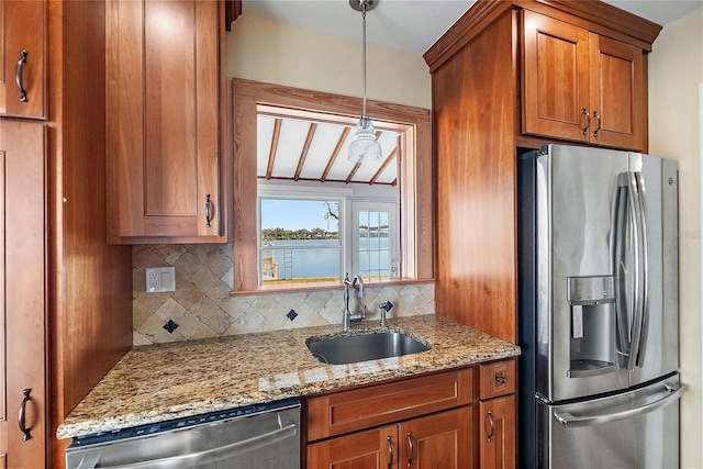 kitchen featuring pendant lighting, sink, backsplash, stainless steel appliances, and light stone counters