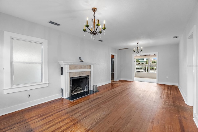 unfurnished living room featuring an inviting chandelier, a fireplace, and hardwood / wood-style floors