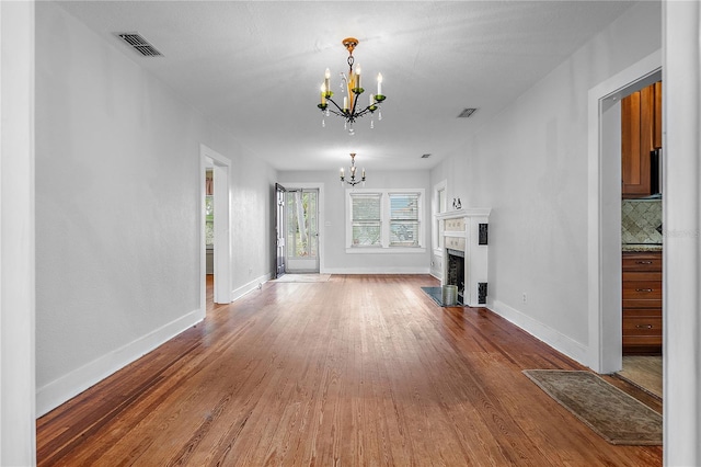 unfurnished living room featuring wood-type flooring and an inviting chandelier