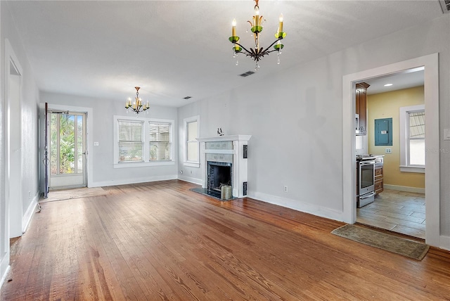 unfurnished living room featuring wood-type flooring, a chandelier, and electric panel