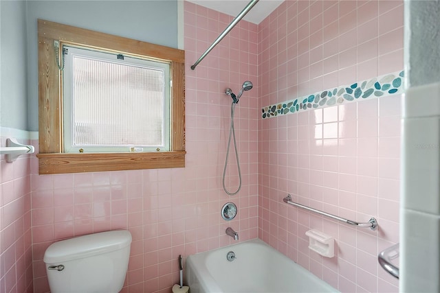 bathroom featuring tile walls, tiled shower / bath combo, and toilet