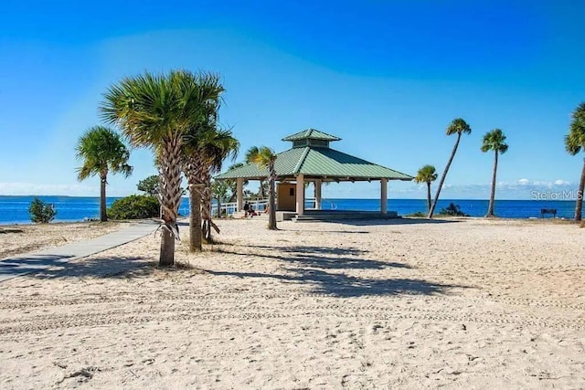 surrounding community with a gazebo, a water view, and a view of the beach