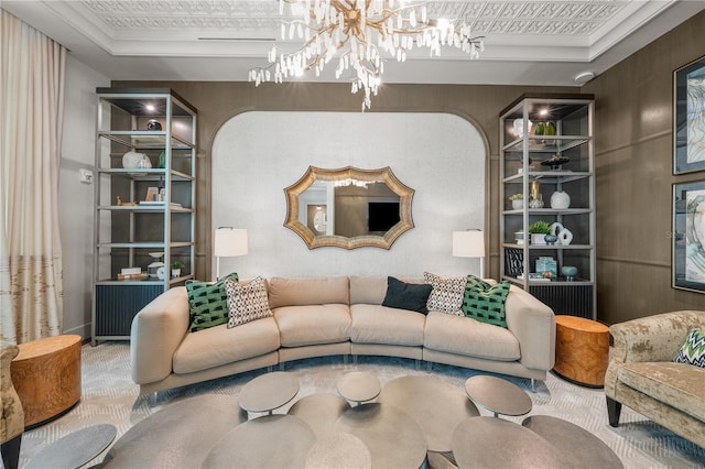 carpeted living area with an inviting chandelier, an ornate ceiling, built in shelves, and a raised ceiling