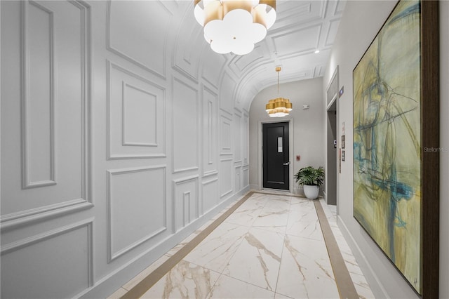 entryway with marble finish floor, vaulted ceiling, and a decorative wall