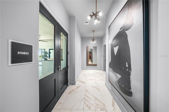 corridor with marble finish floor, visible vents, and a notable chandelier