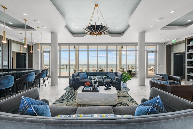 living area featuring a tray ceiling, marble finish floor, plenty of natural light, and recessed lighting