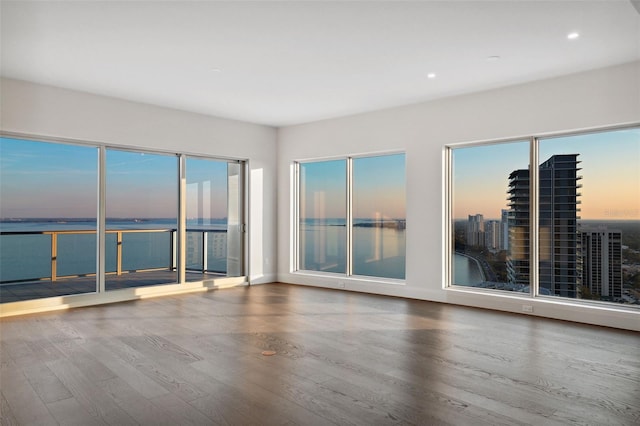 empty room with a water view, wood finished floors, and recessed lighting