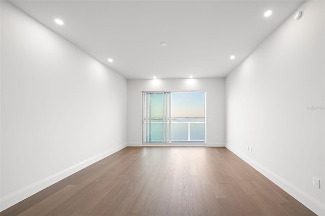 spare room with recessed lighting, baseboards, and wood finished floors