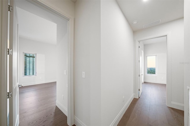 hallway featuring dark wood-style floors, visible vents, and baseboards