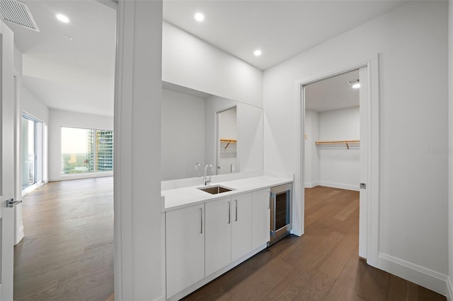 bathroom with beverage cooler, visible vents, wood finished floors, a walk in closet, and recessed lighting