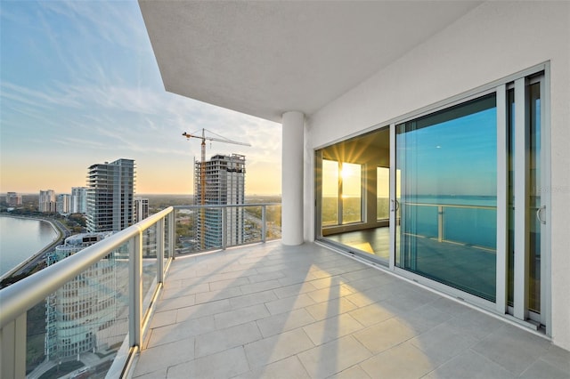 balcony at dusk with a view of city and a water view