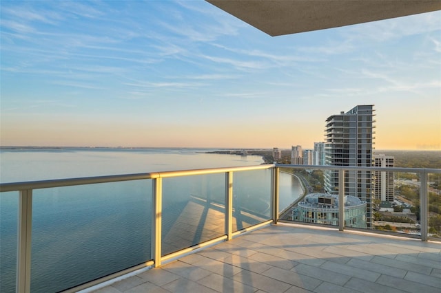 balcony at dusk with a view of city and a water view