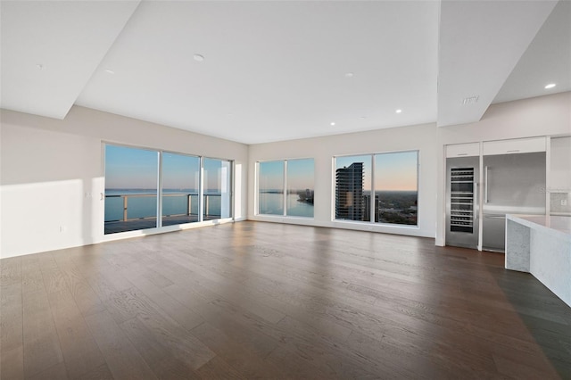 unfurnished living room featuring dark wood-type flooring, a wealth of natural light, beverage cooler, and recessed lighting