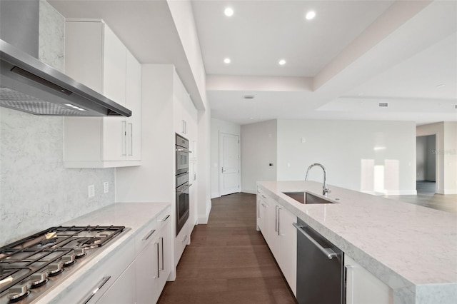 kitchen featuring stainless steel appliances, white cabinetry, a sink, and wall chimney exhaust hood