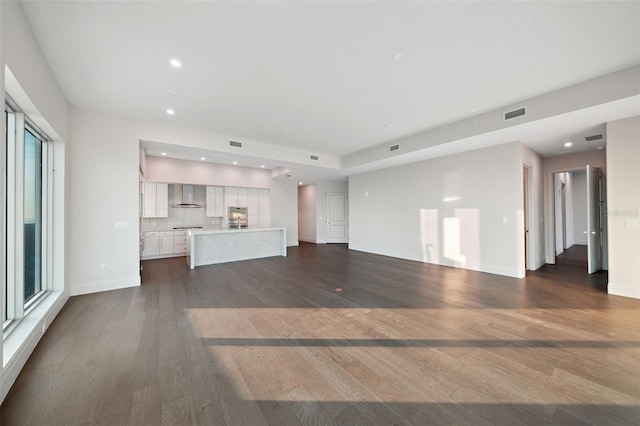 unfurnished living room featuring baseboards, dark wood finished floors, visible vents, and recessed lighting