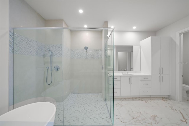 bathroom with toilet, vanity, marble finish floor, a soaking tub, and a shower stall