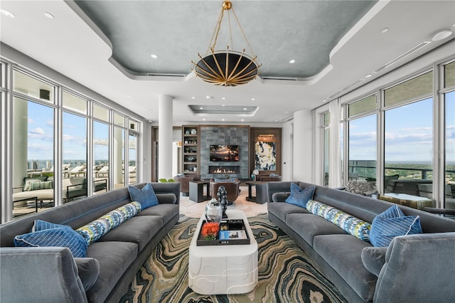 living room featuring built in shelves, a fireplace, a raised ceiling, and recessed lighting