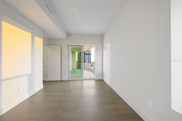 spare room with baseboards, visible vents, and wood finished floors