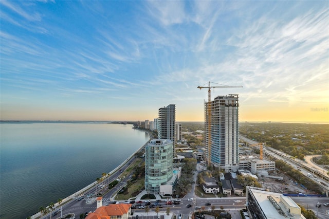 aerial view at dusk featuring a water view and a city view