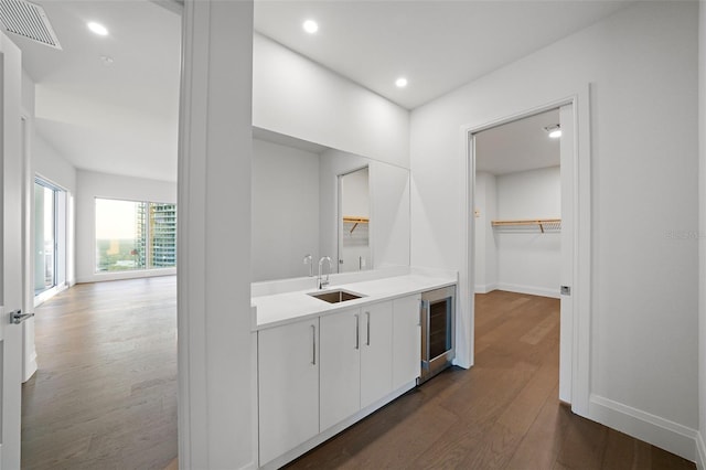 indoor wet bar featuring beverage cooler, dark wood-style floors, baseboards, and recessed lighting
