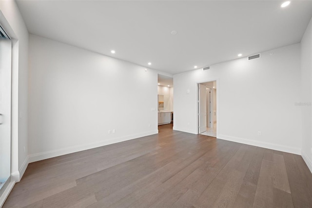 unfurnished room with recessed lighting, wood finished floors, and baseboards