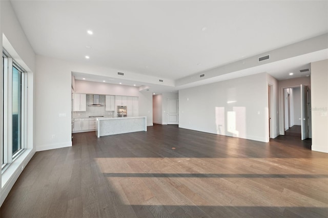 unfurnished living room featuring dark wood-style flooring, recessed lighting, and baseboards