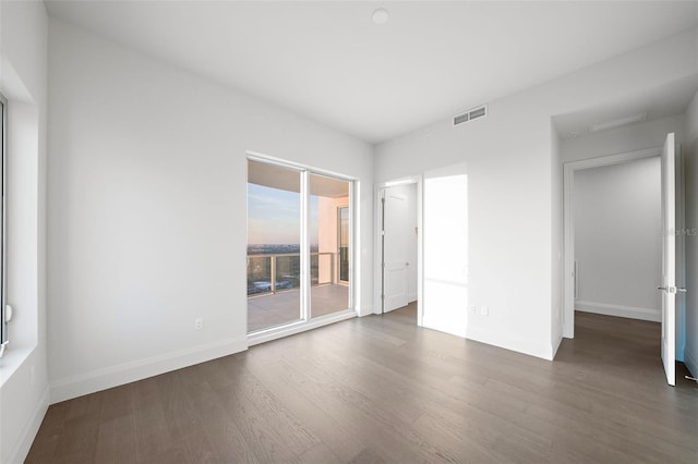 unfurnished bedroom featuring wood finished floors, baseboards, and access to outside