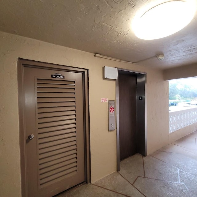 hallway featuring elevator and a textured ceiling