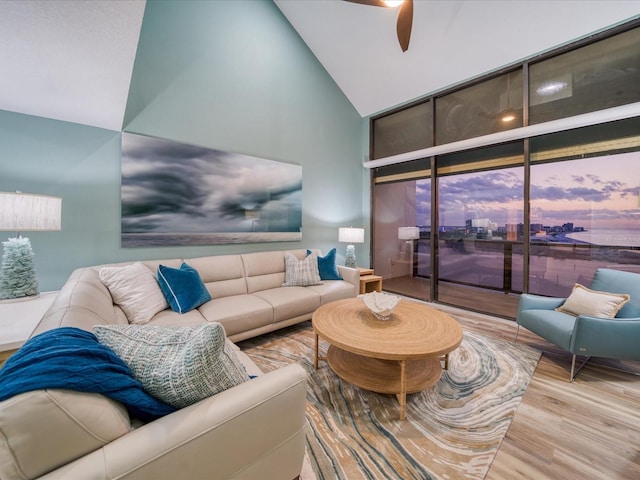 living room with high vaulted ceiling, ceiling fan, and light hardwood / wood-style flooring