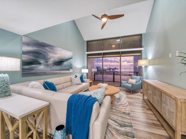 living room with light hardwood / wood-style floors, high vaulted ceiling, and ceiling fan