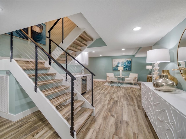 stairway with wine cooler and hardwood / wood-style flooring