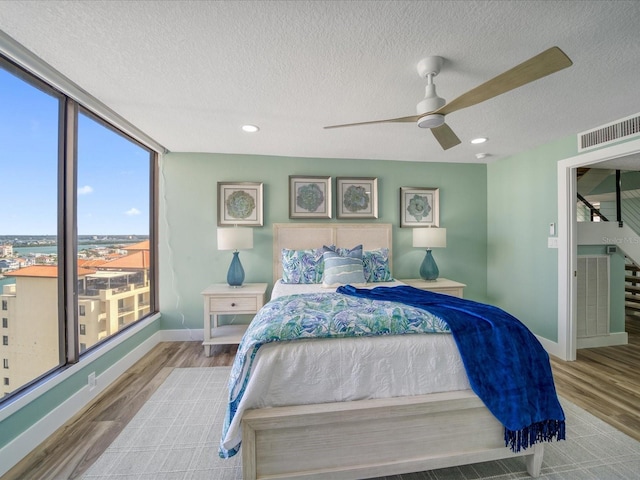 bedroom with a textured ceiling, ceiling fan, and light wood-type flooring