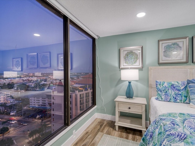 bedroom with a wall of windows and hardwood / wood-style flooring