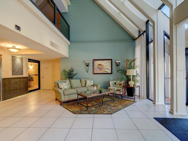 living room with high vaulted ceiling, light tile patterned floors, and decorative columns