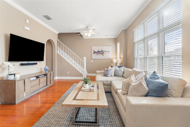 living room with ceiling fan, ornamental molding, and light hardwood / wood-style flooring