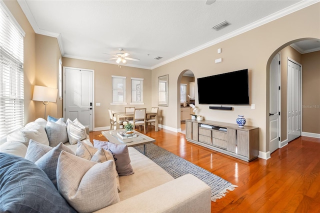 living room with crown molding, wood-type flooring, and ceiling fan